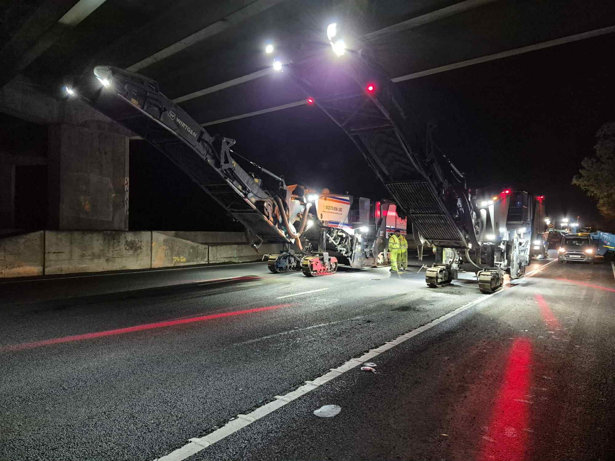 Two road planers working under a bridge